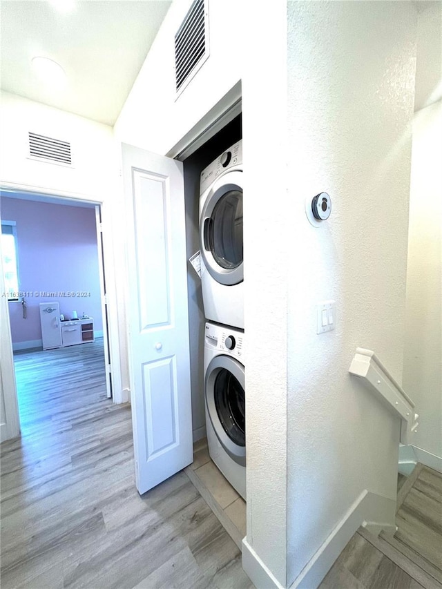 clothes washing area featuring stacked washer and dryer and light hardwood / wood-style floors