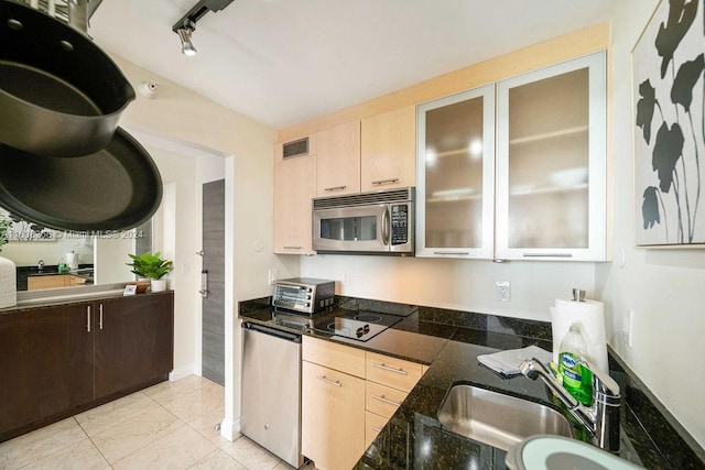 kitchen with light brown cabinetry, stainless steel appliances, track lighting, and light tile patterned floors