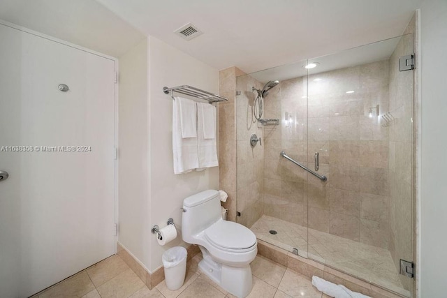 bathroom featuring toilet, a shower with door, and tile patterned flooring