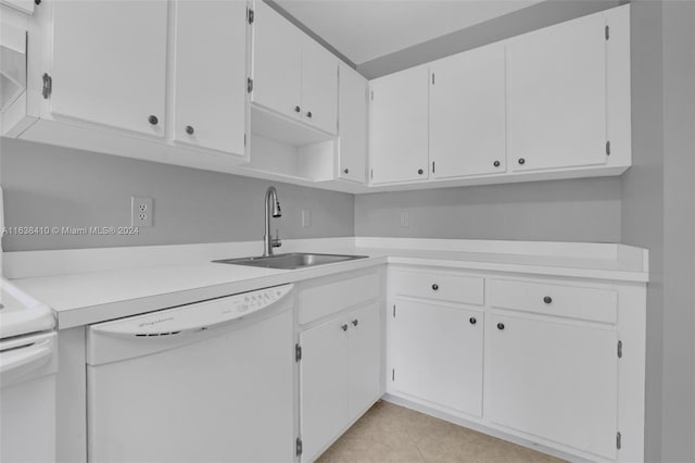 kitchen featuring white dishwasher, range, white cabinets, light tile patterned floors, and sink