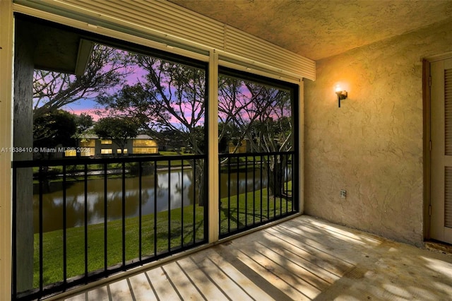 balcony at dusk featuring a water view