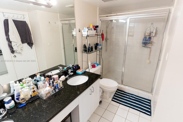 bathroom featuring toilet, vanity, tile patterned floors, and a shower with shower door