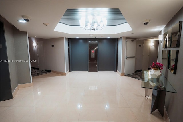 hall featuring light tile patterned flooring, elevator, and a chandelier