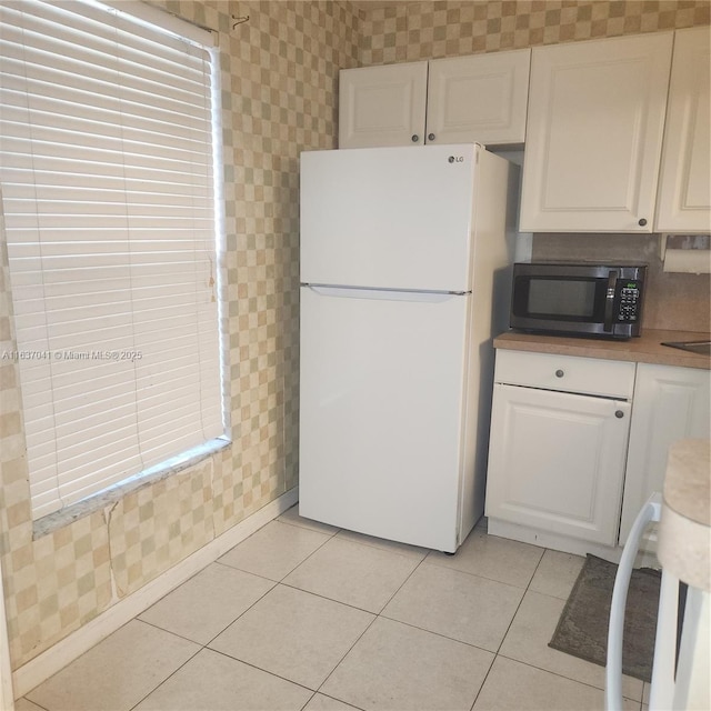 5800 NW 64th Ave Unit 108, Tamarac, FL 33319 - kitchen featuring freestanding refrigerator, stainless steel microwave, white cabinets, wallpapered walls, and light tile patterned floors