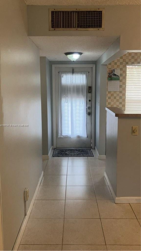 5800 NW 64th Ave Unit 108, Tamarac, FL 33319 - corridor with a textured ceiling, light tile patterned flooring, and baseboards