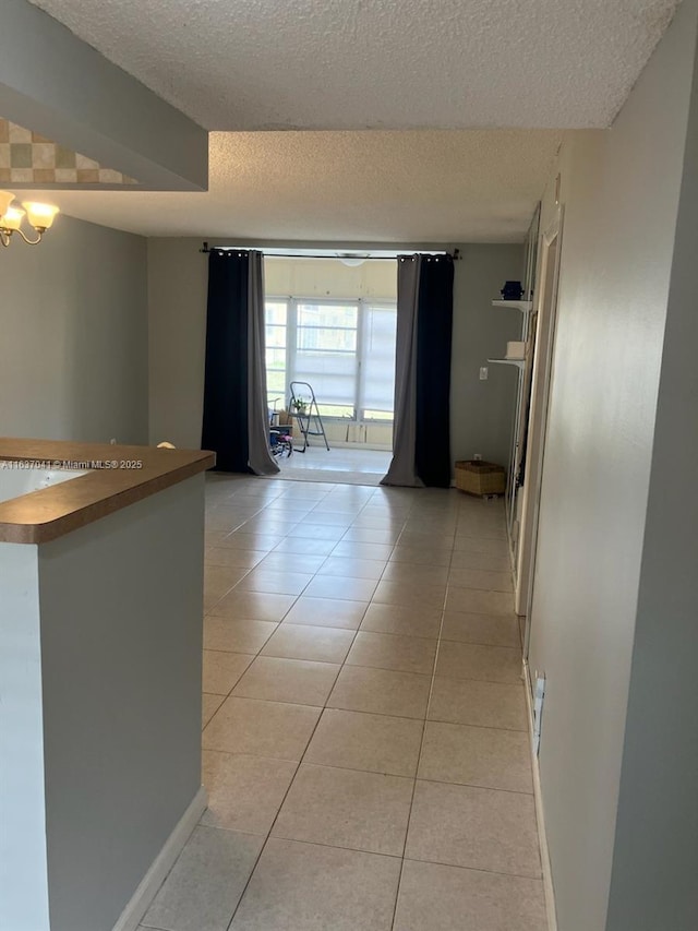 5800 NW 64th Ave Unit 108, Tamarac, FL 33319 - hall featuring a textured ceiling, light tile patterned flooring, baseboards, and a chandelier