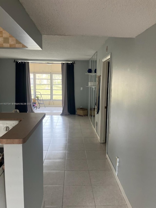 5800 NW 64th Ave Unit 108, Tamarac, FL 33319 - corridor with a textured ceiling, light tile patterned floors, and baseboards