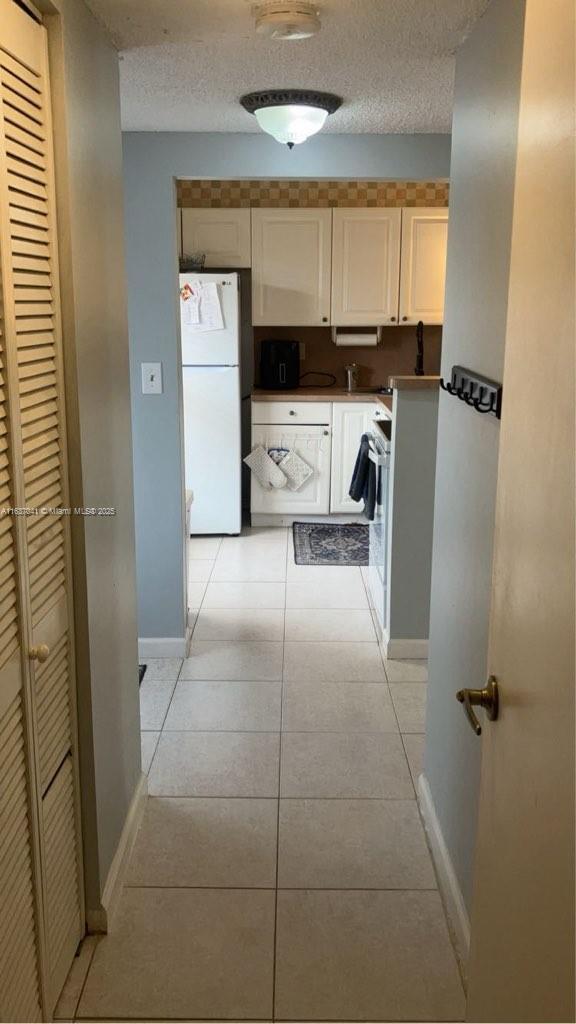 5800 NW 64th Ave Unit 108, Tamarac, FL 33319 - hallway with baseboards, a textured ceiling, and light tile patterned floors
