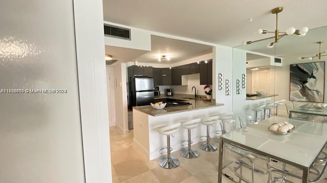 kitchen with stainless steel fridge, sink, kitchen peninsula, hanging light fixtures, and light tile patterned floors