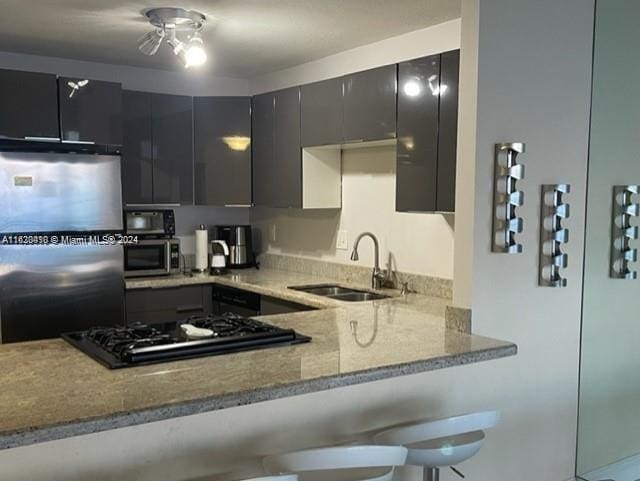 kitchen featuring appliances with stainless steel finishes, light stone countertops, sink, and ceiling fan