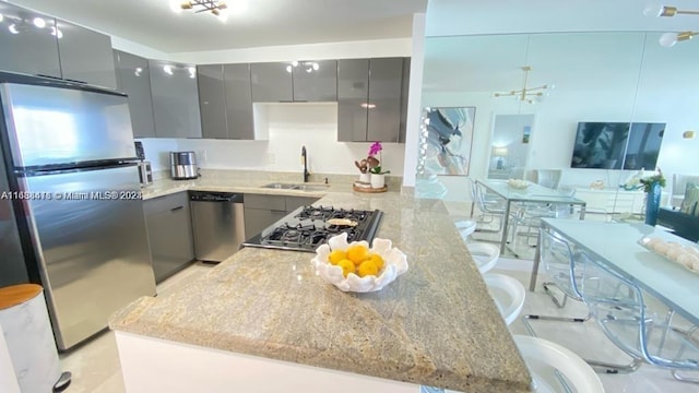 kitchen featuring appliances with stainless steel finishes, a kitchen bar, light stone counters, and gray cabinetry