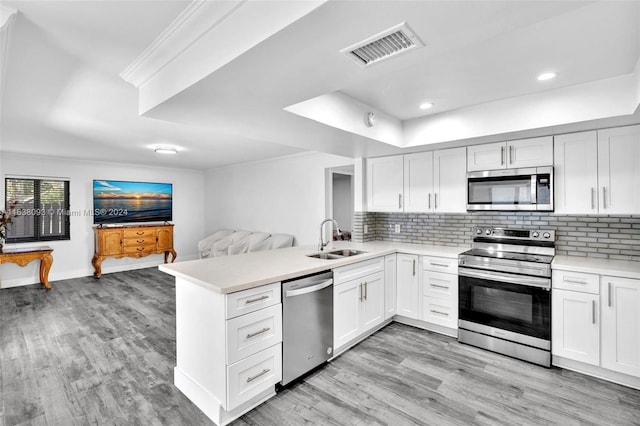 kitchen with tasteful backsplash, stainless steel appliances, white cabinets, light hardwood / wood-style flooring, and sink