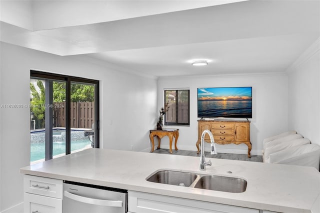 kitchen featuring crown molding, white cabinets, sink, stainless steel dishwasher, and light stone counters