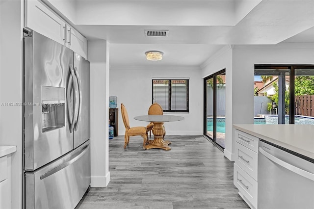 kitchen featuring light hardwood / wood-style flooring, white cabinets, stainless steel appliances, and plenty of natural light