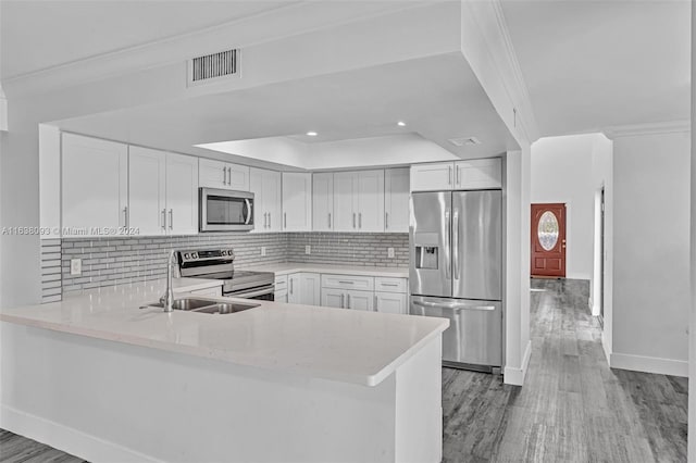 kitchen with kitchen peninsula, white cabinets, light wood-type flooring, and stainless steel appliances