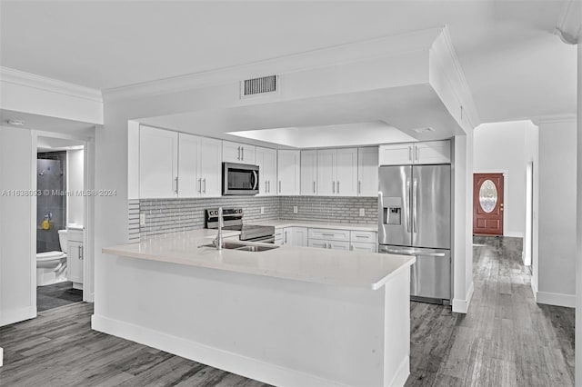 kitchen with decorative backsplash, hardwood / wood-style floors, white cabinetry, appliances with stainless steel finishes, and kitchen peninsula