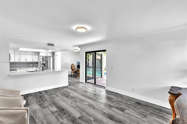 unfurnished living room with sink, french doors, ornamental molding, and hardwood / wood-style floors