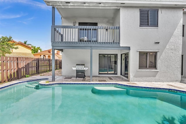 rear view of house with a fenced in pool and a balcony