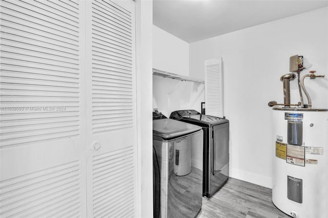 clothes washing area featuring water heater, independent washer and dryer, and hardwood / wood-style floors