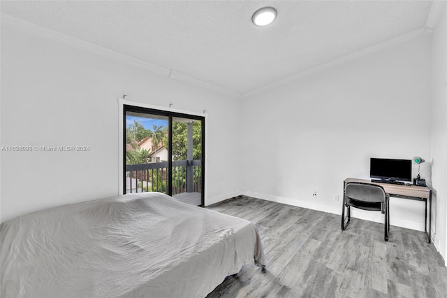 bedroom with wood-type flooring, crown molding, and access to exterior