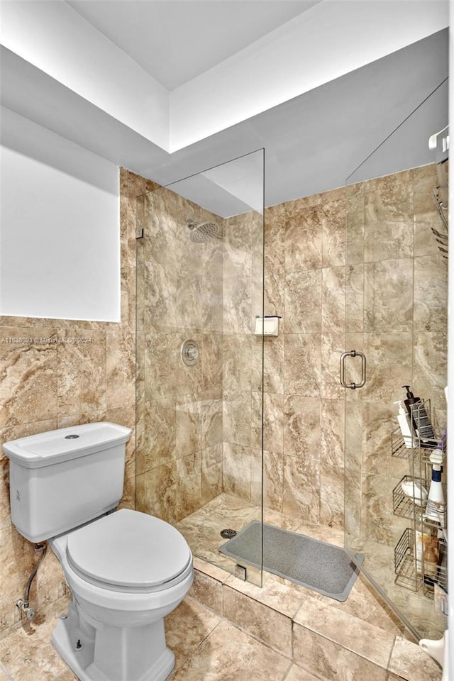 bathroom with a shower with shower door, tile walls, tile patterned flooring, and toilet