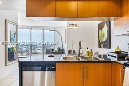 kitchen with brown cabinetry, dark countertops, dishwasher, and a sink