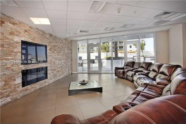 tiled living area featuring a drop ceiling, a fireplace, and visible vents