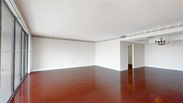 unfurnished room with dark wood-type flooring and a notable chandelier