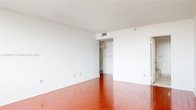 unfurnished bedroom with wood-type flooring and ensuite bathroom