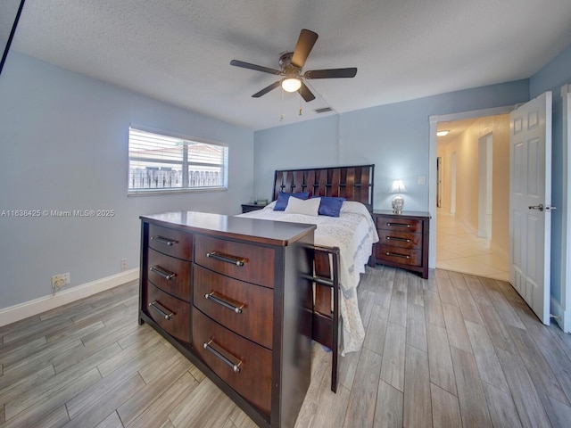 bedroom featuring baseboards, visible vents, a ceiling fan, wood tiled floor, and a textured ceiling