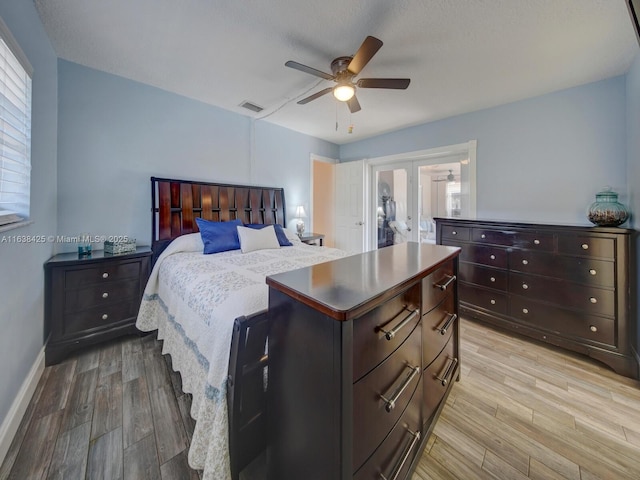 bedroom with french doors, light wood finished floors, visible vents, a ceiling fan, and baseboards