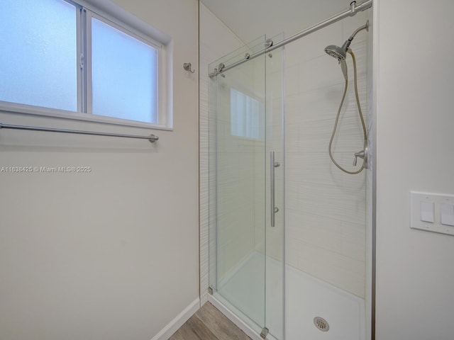 bathroom featuring a shower stall, baseboards, and wood finished floors