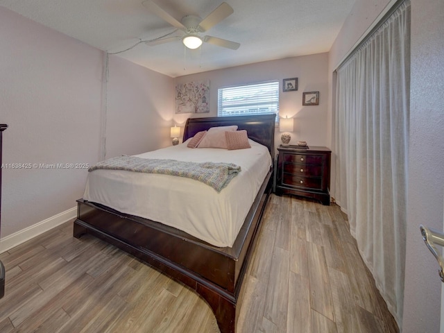 bedroom with light wood-type flooring, ceiling fan, and baseboards