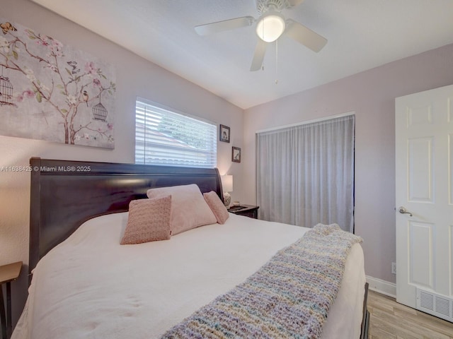 bedroom featuring baseboards, wood finished floors, visible vents, and a ceiling fan