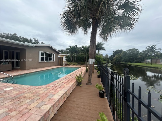 outdoor pool featuring a water view and a patio