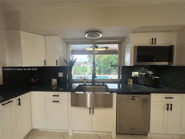 kitchen featuring white cabinetry, a sink, backsplash, and stainless steel dishwasher