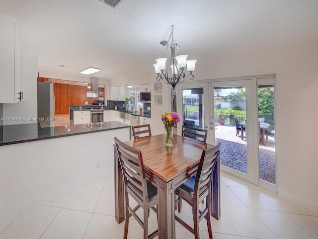 dining area featuring a textured ceiling, an inviting chandelier, and light tile patterned floors