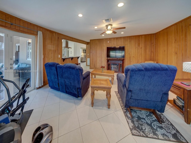 living room with visible vents, wood walls, and light tile patterned floors