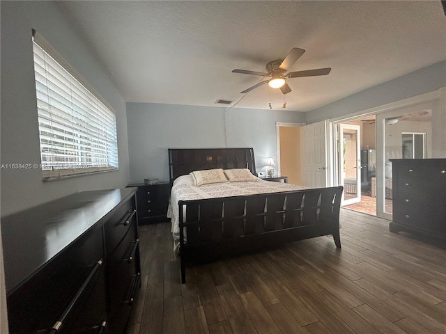 bedroom with a textured ceiling, dark wood finished floors, visible vents, and a ceiling fan