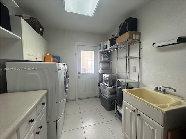 clothes washing area with light tile patterned floors, independent washer and dryer, a sink, and cabinet space