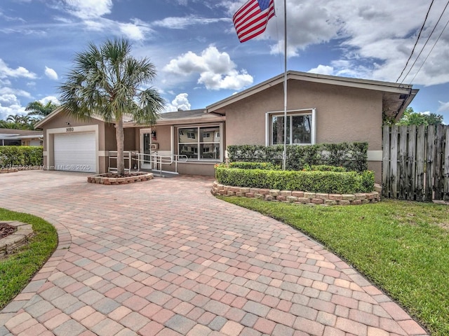 single story home featuring stucco siding, an attached garage, fence, decorative driveway, and a front yard