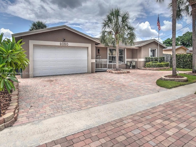 ranch-style house featuring a garage, decorative driveway, fence, and stucco siding