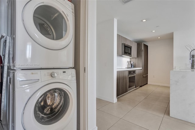 washroom featuring light tile patterned flooring and stacked washing maching and dryer