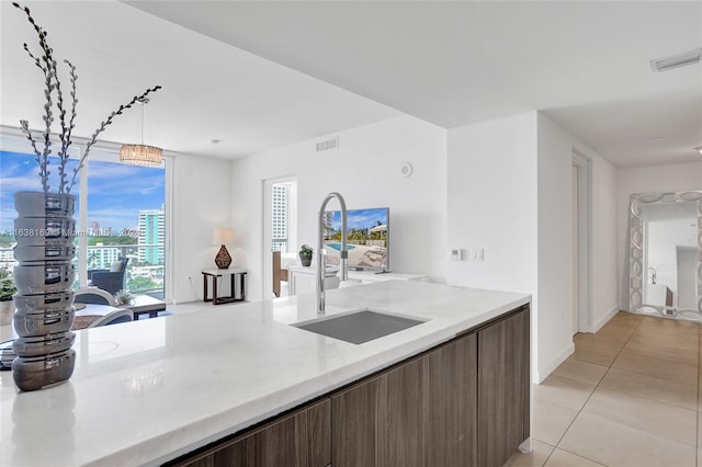 kitchen featuring a notable chandelier, sink, light tile patterned flooring, and hanging light fixtures