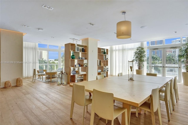 dining space with floor to ceiling windows and light hardwood / wood-style floors