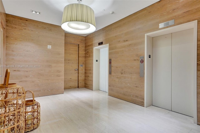 corridor with elevator and wooden walls