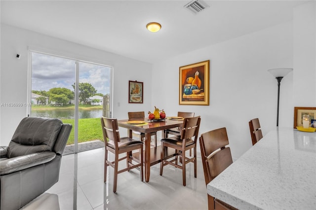 dining area with a water view, a wealth of natural light, and light tile patterned floors