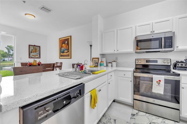 kitchen featuring light tile patterned flooring, kitchen peninsula, stainless steel appliances, and white cabinets