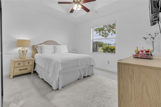 tiled bedroom with a tray ceiling and ceiling fan