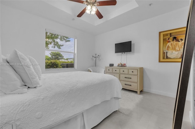 tiled bedroom featuring ceiling fan and a raised ceiling